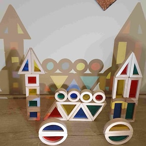 May include: A set of colourful wooden blocks in the shape of triangles and circles. The blocks are arranged in a castle-like formation. The blocks are made of natural wood and have a clear, stained finish. The blocks are a great educational toy for children.