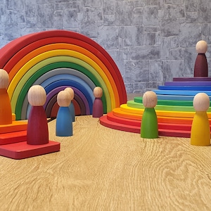 May include: A rainbow-colored wooden arch with a set of colorful wooden figures. The arch is made of 12 pieces of wood, each a different color of the rainbow. The figures are all the same size and shape, but each is painted a different color.