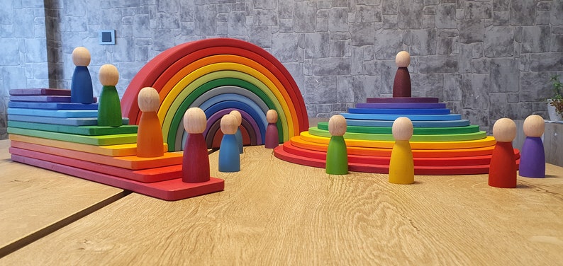 May include: A rainbow-colored wooden arch with a set of colorful wooden figures. The arch is made of 12 pieces of wood, each a different color of the rainbow. The figures are all the same size and shape, but each is painted a different color.