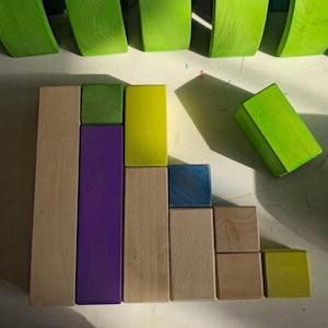 May include: A collection of colorful wooden blocks in various shapes and sizes. The blocks are arranged in a visually appealing pattern, with a mix of natural wood, green, purple, yellow, and blue hues. The image is well-lit, highlighting the textures and colors of the blocks.