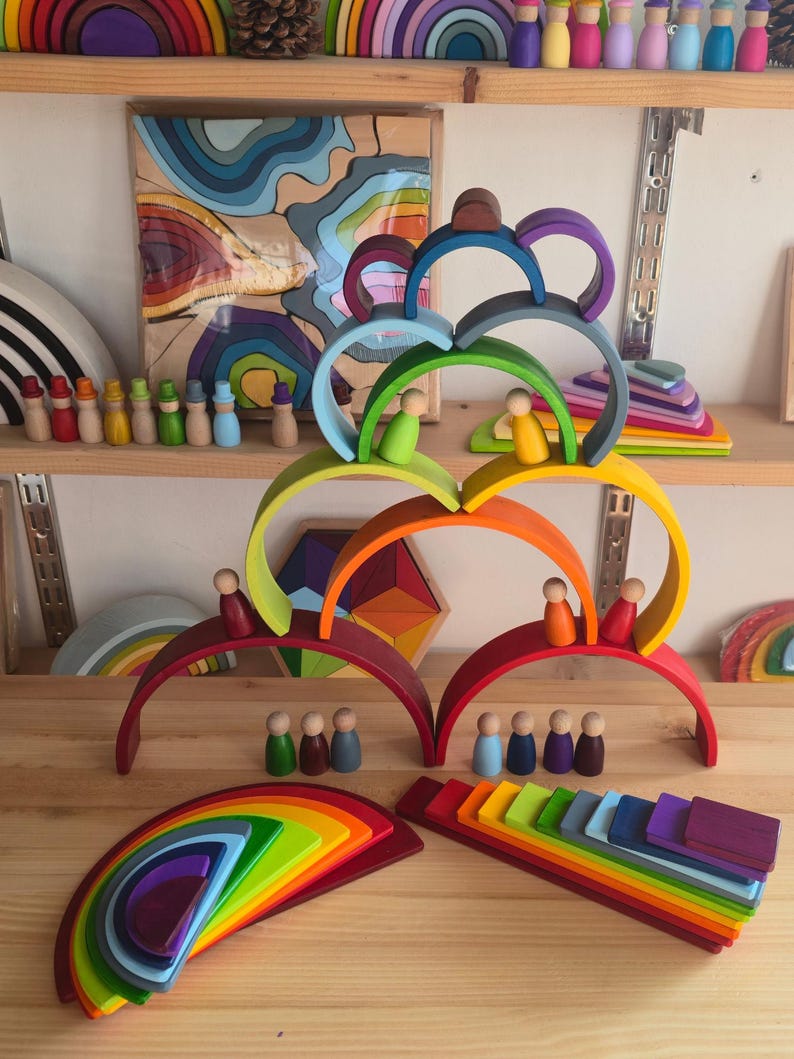 May include: A collection of wooden rainbow stacking arches and small peg dolls in various colors. The arches are arranged in a tiered structure, with several peg dolls placed on top of the curves and others standing on the surface below.