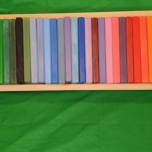 May include: A wooden box filled with colorful wooden blocks. The blocks are arranged in a rainbow pattern, with each block a different shade of color.