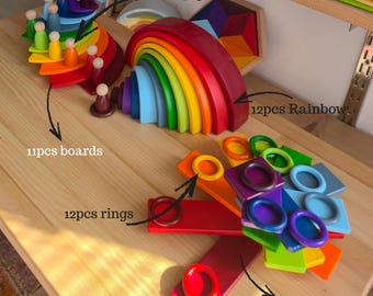 May include: A 58-piece wooden toy set featuring 12 peg dolls, an 11-piece board set, a 12-piece rainbow arch stacker, 12 rings, and 11 cards. The items are painted in various colors including red, orange, yellow, green, blue, and purple.