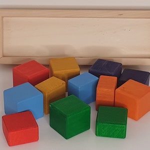 May include: A set of 10 wooden blocks in various colors, including red, orange, yellow, green, blue, and purple. The blocks are arranged in a semi-circle on a white surface.