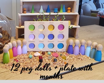 May include: A wooden plate with 12 colorful peg dolls and a circular cutout for each month of the year. The plate is labeled with the months of the year. The peg dolls are arranged in a row below the plate.