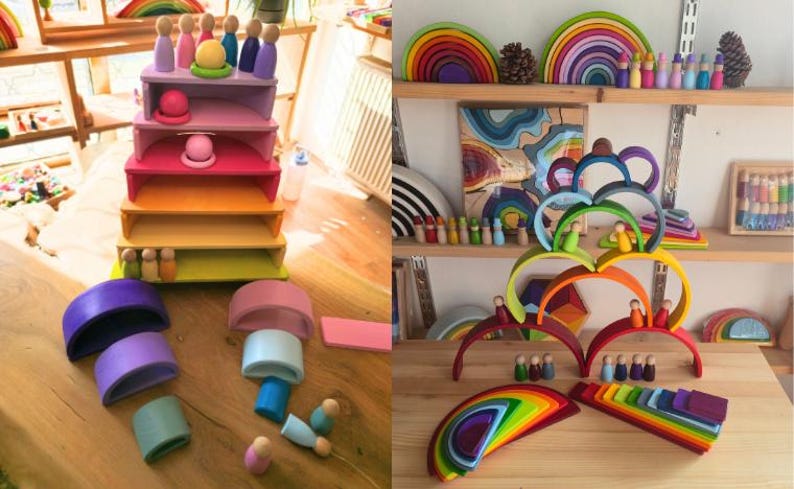 May include: A collection of wooden rainbow stacking arches and small peg dolls in various colors. The set includes semi-circular pieces, rectangular platforms, and arched segments arranged in tiered structures and scattered on a wooden surface.