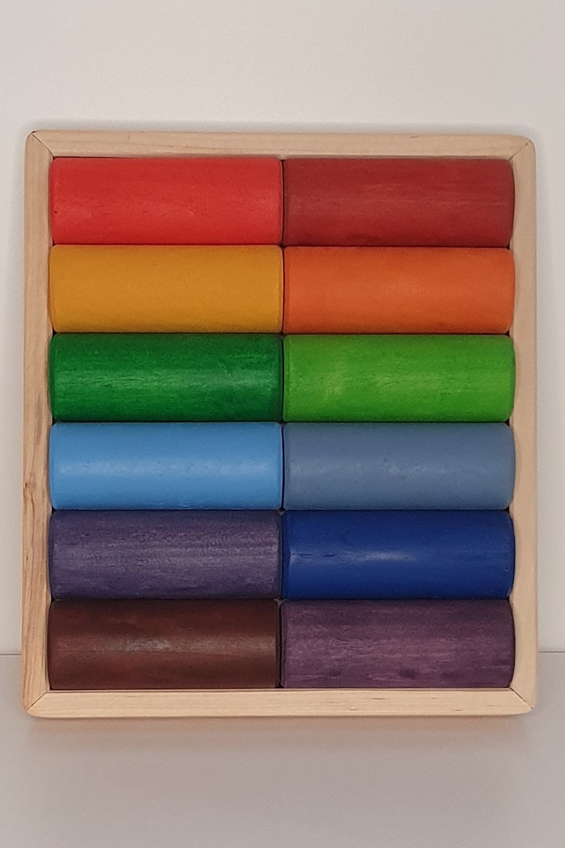 May include: A wooden rainbow stacking toy with 12 colorful cylinders in a wooden frame. The cylinders are arranged in a rainbow pattern, starting with red and ending with purple.