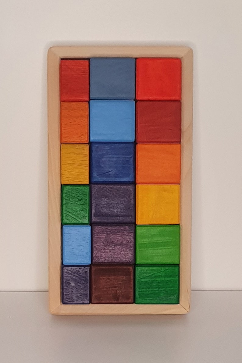May include: A wooden box with a rainbow of colored blocks inside. The blocks are arranged in a grid pattern, with each row containing a different color.