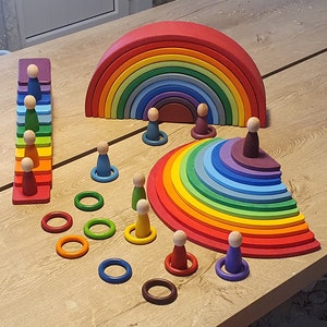 May include: A rainbow wooden arch, a rainbow wooden half-circle, a rainbow wooden staircase, and a set of wooden rings and figures. The toys are made of natural wood and painted in bright colors.