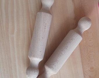 May include: Two wooden rolling pins with rounded handles. The rolling pins are made of light-colored wood and are positioned diagonally across a light-colored wooden surface. The rolling pins are designed for baking and cooking.
