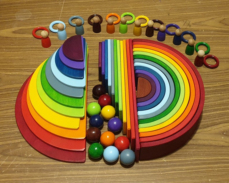 May include: A rainbow-colored wooden stacking toy with a set of colorful wooden people. The toy is made of 12 different colored rings that stack on top of each other. The rings are made of wood and have a smooth finish. The people are also made of wood and have painted faces. The toy is a great way for children to learn about colors and shapes.
