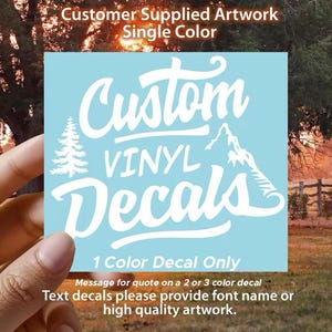 May include: A light blue square vinyl decal featuring white text that reads Custom Vinyl Decals, accompanied by a white graphic of a pine tree and a mountain peak. The decal includes the text Customer Supplied Artwork Single Color.