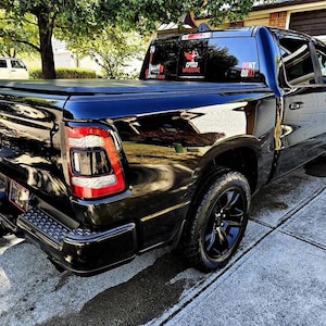 May include: Black pickup truck with a black tonneau cover. The truck has a "Don't Quit!" sticker on the back window and a "C.F.T.D Warrior" sticker on the rear passenger side window.