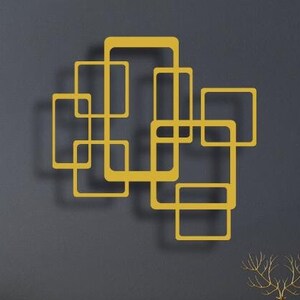 Könnte beinhalten: Ein schwarzer Schrank mit goldenen Akzenten steht vor einer grauen Wand mit einem goldenen geometrischen Wandkunstwerk. Eine weiße Globuslampe und zwei Topfpflanzen befinden sich auf der linken Seite des Schranks. Ein kleiner Topfbaum befindet sich auf der rechten Seite des Schranks.