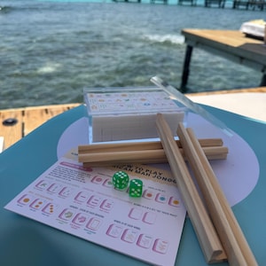 May include: A green table with a set of wooden tiles, two green dice, and a set of instructions for playing "How to Play African Mahjong".