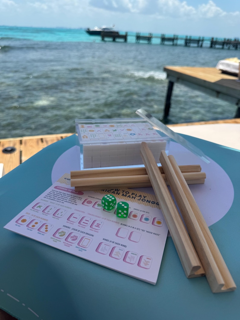 May include: A green table with a set of wooden tiles, two green dice, and a set of instructions for playing "How to Play African Mahjong".