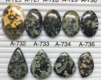 May include: A collection of nine polished cabochon gemstones arranged in two rows. The top row features five oval stones labeled A-725 through A-730, while the bottom row shows four teardrop-shaped stones labeled A-732 through A-736, all displaying dark green, black, and cream-colored orbicular patterns.