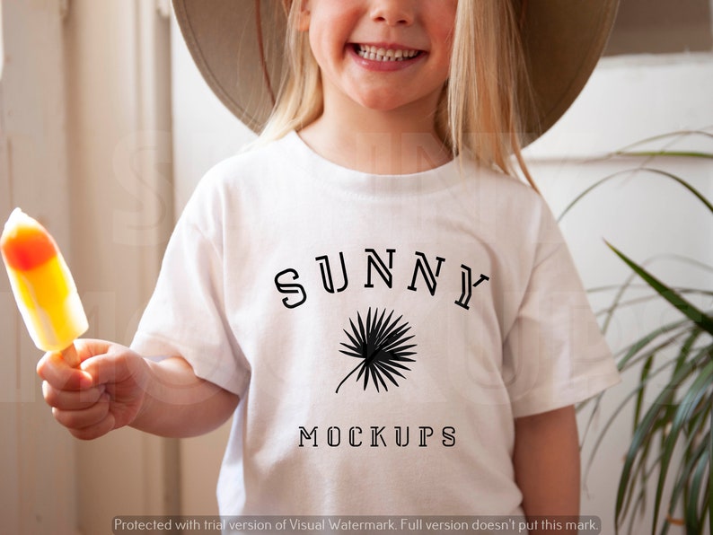 Op de afbeelding: Een wit T-shirt met een zwart grafisch ontwerp met de tekst "SUNNY" met daaronder een palmboomontwerp en de woorden "MOCKUPS" onder de palmboom.