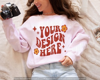 May include: A pink sweatshirt with the text "YOUR DESIGN HERE" in a retro font with orange flowers and stars.