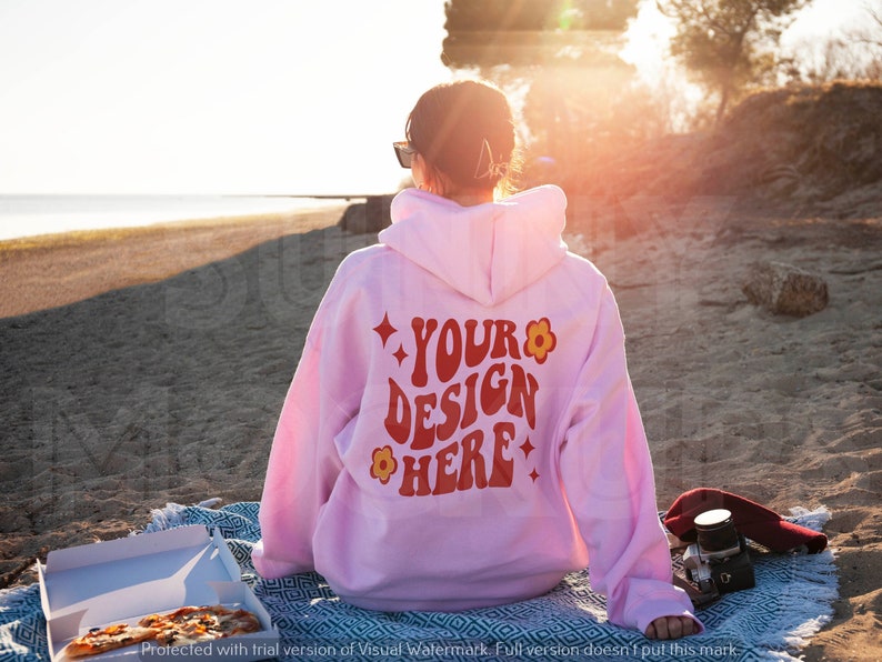 Puede incluir: Una sudadera con capucha rosa con el texto "YOUR DESIGN HERE" en rojo y amarillo en la espalda. La sudadera tiene un dise&ntilde;o de flor y estrella.