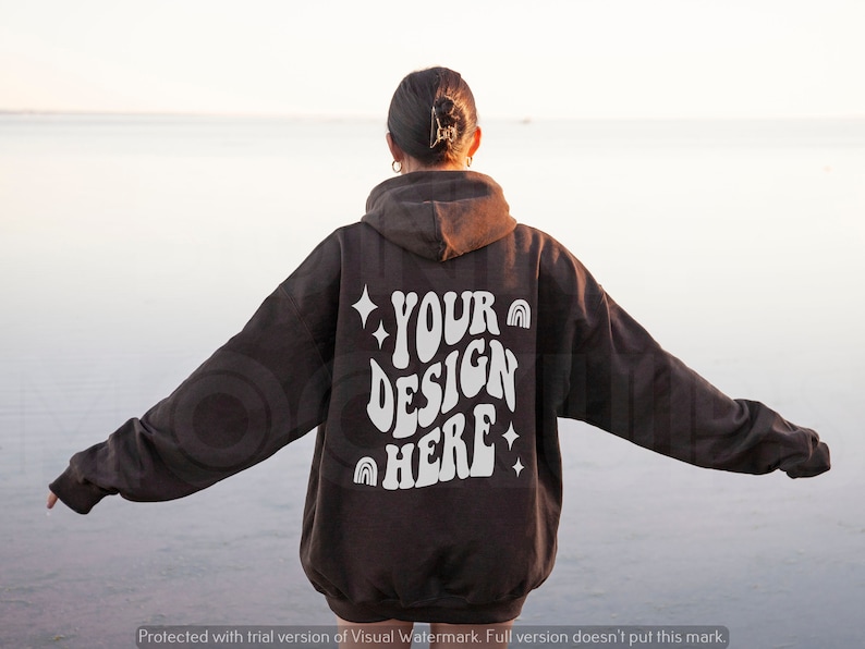 K&ouml;nnte beinhalten: Ein brauner Hoodie mit einem wei&szlig;en Aufdruck auf der R&uuml;ckseite, der "YOUR DESIGN HERE" mit Regenbogen- und Sternen-Akzenten sagt.