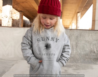 Może przedstawiać: Szara bluza z kapturem z czarnym nadrukiem palmy i tekstem "SUNNY MOCKUPS" z przodu. Młoda osoba nosi bluzę i czerwony beret.