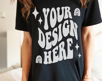 May include: Black t-shirt with a white graphic that says "YOUR DESIGN HERE" in a retro font. The graphic also includes stars and rainbows.