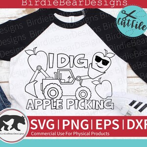 May include: Black and white line art design of a tractor with a smiling apple in the bucket. The text "I DIG APPLE PICKING" is above the tractor. The design is on a white t-shirt.