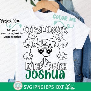 Pu&ograve; includere: T-shirt bianco con un design per la festa di San Patrizio. Il design presenta un trifoglio sorridente con un cappello, circondato da trifogli, e il testo "Cutest Clover In The Patch Joshua". Include il testo "Color Me" e "Project Idea".