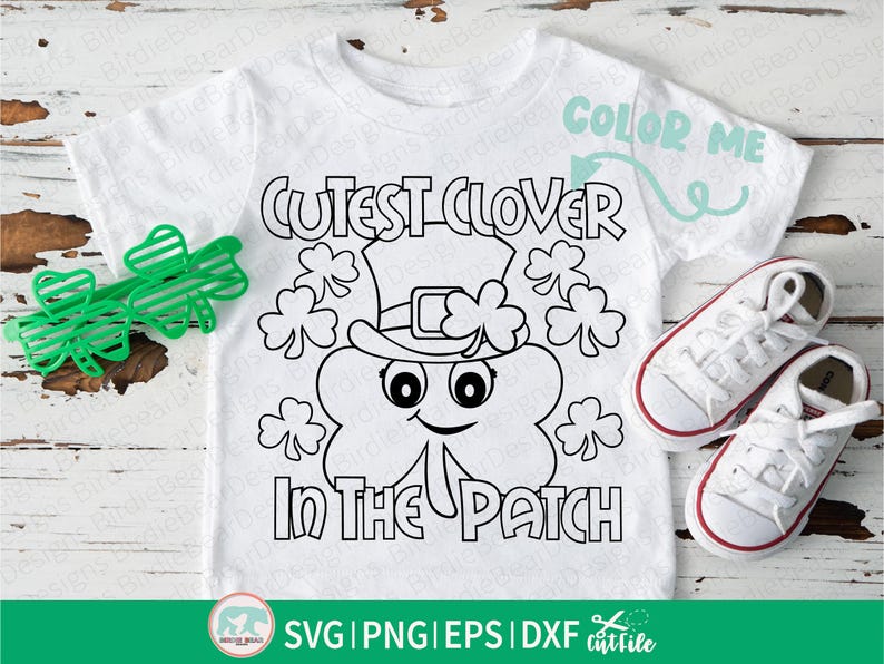 Pu&ograve; includere: Maglietta bianca con un contorno nero di un personaggio a forma di trifoglio con un cappello, con la scritta "Cutest Clover in the Patch". Include occhiali verdi a forma di trifoglio e scarpe da ginnastica bianche con bordi rossi. C'&egrave; anche la scritta "Color Me".