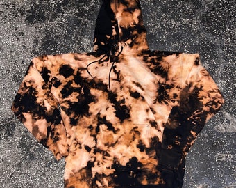 Sudadera con capucha unisex teñida a mano en negro y naranja con técnica tie-dye.