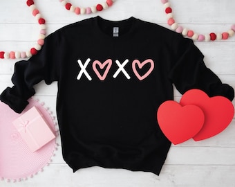 May include: Black sweatshirt with a white graphic of the text "XOXO" with pink hearts.