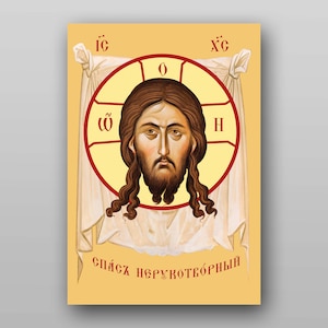 May include: A religious icon depicting the face of Jesus Christ. The icon is painted in a traditional style with a yellow background and red and white accents. The text "Спас Нерукотворный" is written in Cyrillic script at the bottom of the icon.