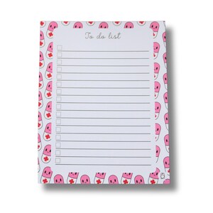 May include: A rectangular notepad with a white background and a border of pink cartoon pills. The notepad has a "To do list" header and lined pages with checkboxes. The pills have smiling faces and red cross symbols.