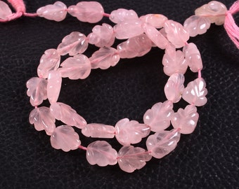 May include: Strands of rose quartz beads, each carved into a leaf shape. The beads are a soft pink color and strung on pink thread. The leaf carvings have detailed veining.