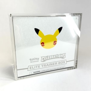May include: A clear acrylic display case holding a Pokémon Celebrations Elite Trainer Box. The box features a yellow Pikachu design with black ears and the numbers 2 and 5. The box is white with black text.