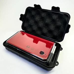 May include: A red Nintendo 3DS handheld game console inside a black protective case. The case is open, revealing the console and two silver styluses. The console has a glossy finish and features Mario-themed icons.