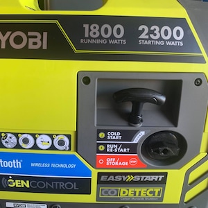 May include: A yellow and black Ryobi generator with a black handle and a blue Bluetooth logo. The generator has a digital display showing 1800 running watts and 2300 starting watts. It also features a cold start, run/re-start, and off/storage buttons. The generator has a black and yellow easy start button and a CO Detect feature.