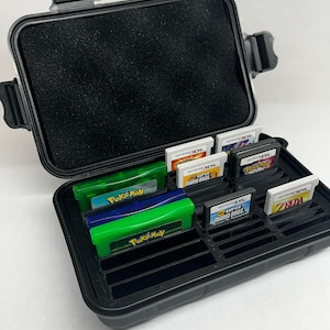 以下が含まれることがあります： 黒いハードケースには、フォーム製の内部にさまざまなビデオゲームカートリッジが入っています。カートリッジは、ニンテンドーDSとゲームボーイアドバンスのシステム用です。カートリッジには、ポケモン、スーパーマリオブラザーズ、ゼルダなど、さまざまなゲームが含まれています。