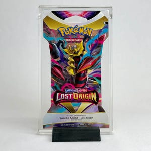 Può includere: Un pacchetto booster di Pokémon Spada e Scudo - Origine Perduta, racchiuso in un supporto di plastica trasparente. Il pacchetto presenta il logo Pokémon e il testo "Lost Origin". Il supporto è nero.