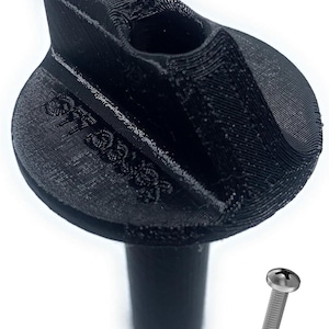 May include: Black 3D-printed bottle stopper with a rounded top and a cylindrical stem. The top features a curved design with a recessed area. A small silver screw is next to the stopper.