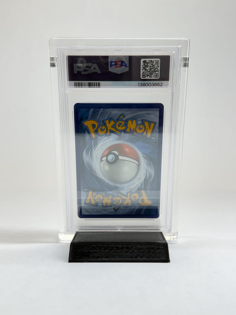 May include: A graded Pok&eacute;mon trading card in a clear plastic case. The card features a blue background with a white and red Pok&eacute;ball design. The case has a PSA label with a QR code and serial number.