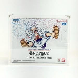 Może przedstawiać: Przezroczysta akrylowa gablota z pudełkiem do gry karcianej One Piece. Pudełko zawiera kolorową ilustrację postaci i tekst "AWAKENING OF THE NEW ERA ONE PIECE CARD GAME". Pudełko jest oznaczone jako "English Ver. OP-05".