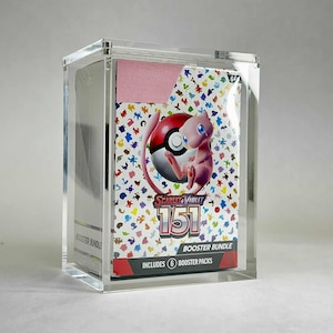 May include: A clear acrylic display case holding a "Scarlet & Violet 151 Booster Bundle" with a pink background. The bundle features a colorful design with a pink Mew and a red and white Poké Ball.