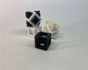 May include: Three 3D printed cubes, one black, one white and one beige. The black cube is on the bottom, the white cube is on top of the black cube, and the beige cube is on top of the white cube.