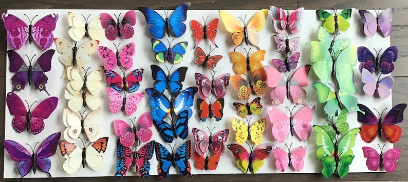 May include: A collection of 3D butterfly wall decor in various colors, including purple, pink, blue, green, orange, and yellow. The butterflies are made of a lightweight material and have a 3D effect, making them appear to be flying.