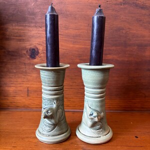 May include: Two green ceramic candle holders with frog designs and black candles.