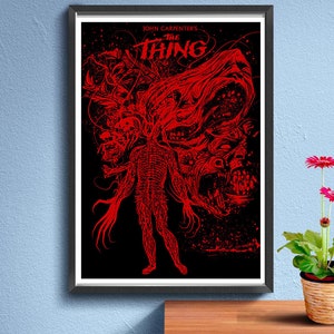 Puede incluir: Un póster rojo y negro con el título "John Carpenter's The Thing" y un gráfico de una criatura monstruosa con múltiples cabezas y extremidades.