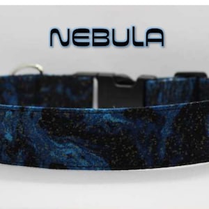 May include: A blue and black dog collar with a nebula print and a silver buckle. The collar has the word "NEBULA" printed on it in white.