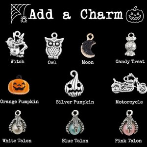 Op de afbeelding: Een selectie Halloween-charms, waaronder een heks, een uil, een maan, een snoepje, een oranje pompoen, een zilveren pompoen, een motorfiets, een witte klauw, een blauwe klauw en een roze klauw.